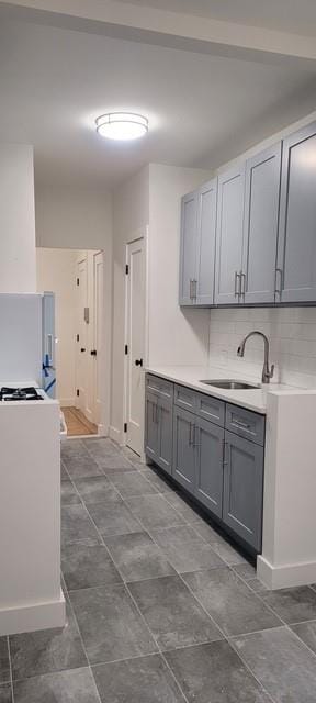 kitchen featuring backsplash, gray cabinets, white refrigerator, and sink