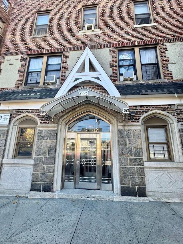 view of exterior entry featuring brick siding and cooling unit