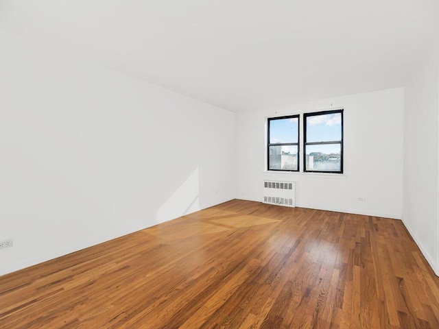 unfurnished room with radiator heating unit and hardwood / wood-style flooring