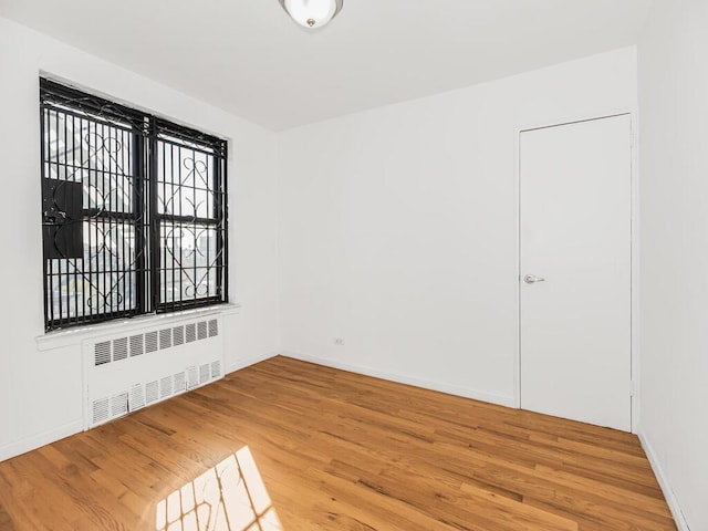 spare room featuring radiator heating unit and hardwood / wood-style floors