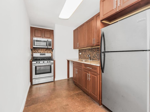 kitchen with decorative backsplash, appliances with stainless steel finishes, light stone counters, and sink