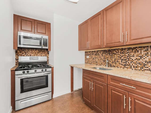 kitchen featuring light stone countertops, appliances with stainless steel finishes, backsplash, and sink