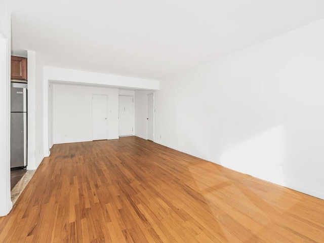 unfurnished bedroom featuring stainless steel fridge, a closet, and light wood-type flooring