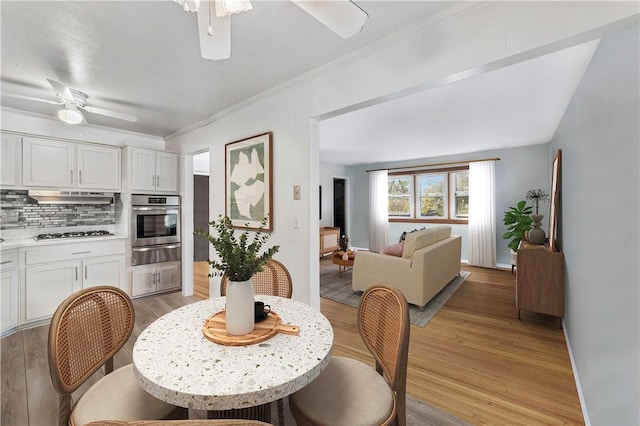 dining room featuring ceiling fan, ornamental molding, and light wood-type flooring