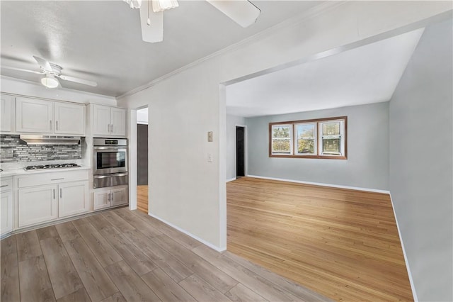 kitchen featuring ventilation hood, backsplash, appliances with stainless steel finishes, white cabinets, and light wood-type flooring