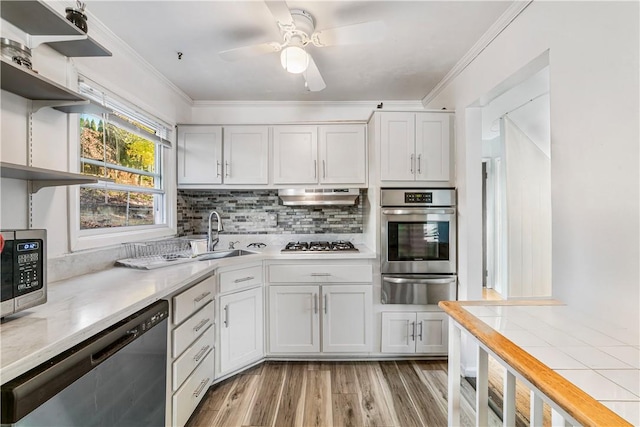 kitchen with white cabinets, appliances with stainless steel finishes, light wood-type flooring, and sink