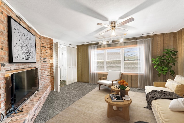 carpeted living room with wooden walls, ceiling fan, and a textured ceiling