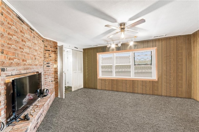 unfurnished living room with carpet flooring, wooden walls, and brick wall