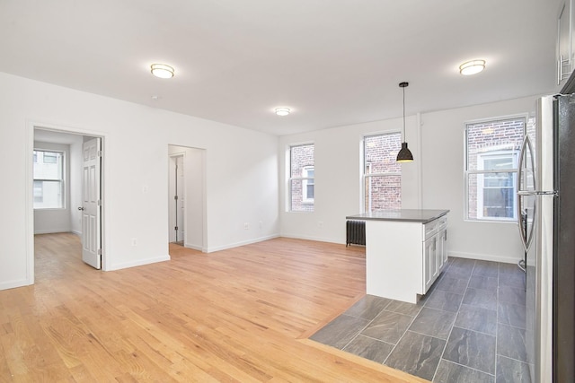 interior space featuring stainless steel fridge, dark hardwood / wood-style flooring, a healthy amount of sunlight, and hanging light fixtures