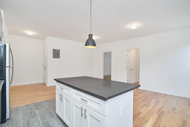 kitchen with electric panel, hanging light fixtures, hardwood / wood-style flooring, stainless steel fridge, and white cabinetry