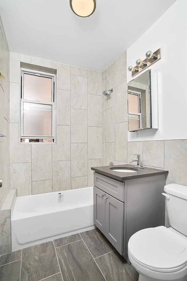 full bathroom featuring vanity, toilet, tile walls, and plenty of natural light