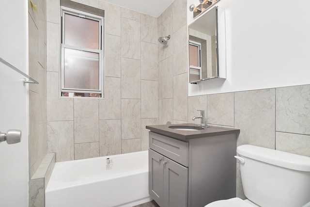 full bathroom with vanity, tiled shower / bath combo, toilet, and tile walls