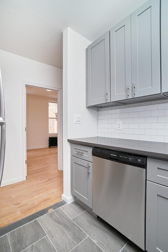 kitchen with backsplash, dishwasher, gray cabinetry, and dark wood-type flooring