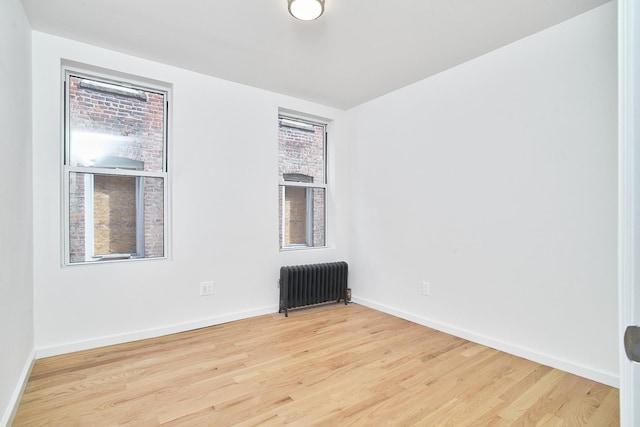 empty room with radiator, plenty of natural light, and light hardwood / wood-style floors