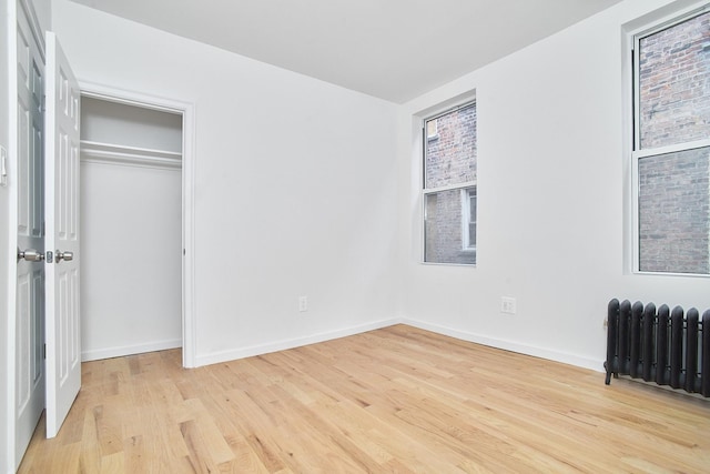 unfurnished bedroom with light hardwood / wood-style floors and radiator