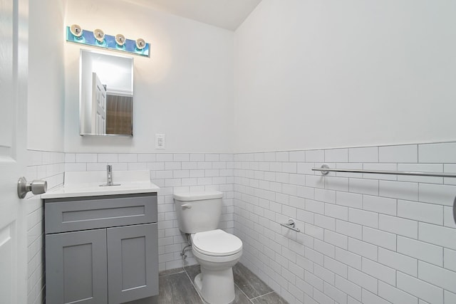 bathroom featuring hardwood / wood-style floors, vanity, toilet, and tile walls