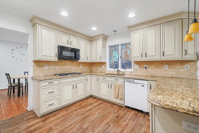 kitchen featuring backsplash, white dishwasher, sink, light hardwood / wood-style flooring, and decorative light fixtures