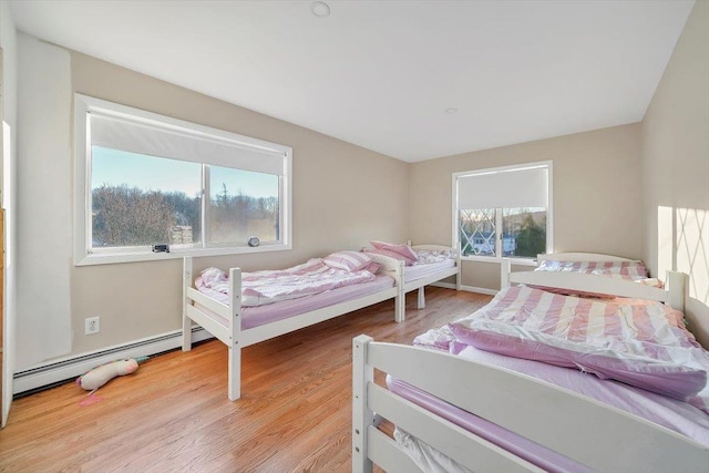 bedroom featuring light hardwood / wood-style floors and a baseboard heating unit