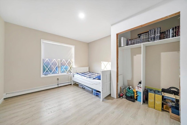 bedroom featuring hardwood / wood-style floors and a baseboard heating unit