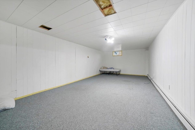 basement with wood walls, carpet floors, and a baseboard radiator