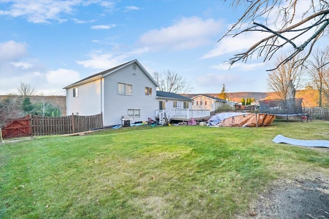 rear view of house with a trampoline, a pool side deck, and a lawn