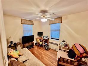 836 Tilden St Unit 6K, Bronx, NY 10467 - living area featuring a ceiling fan, radiator heating unit, wood finished floors, and a desk