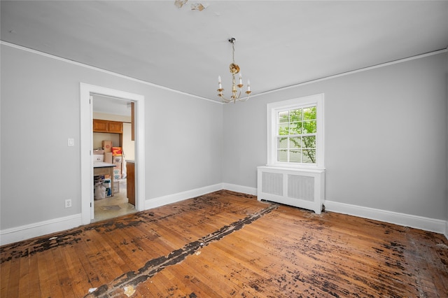 empty room featuring radiator, hardwood / wood-style flooring, baseboards, and a chandelier