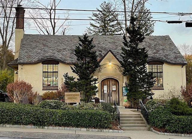 view of front of home featuring a chimney, a high end roof, and stucco siding