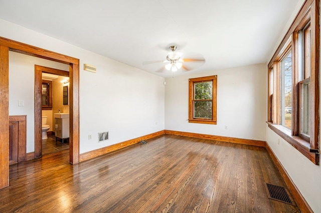 spare room with dark hardwood / wood-style floors, a wealth of natural light, and ceiling fan