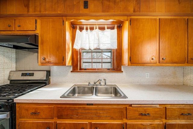 kitchen with ventilation hood, backsplash, sink, and stainless steel gas range