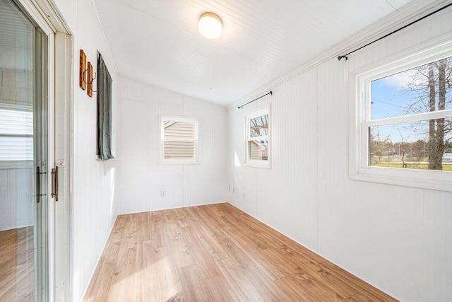 unfurnished room with wood walls, light hardwood / wood-style flooring, and vaulted ceiling