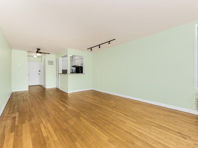 unfurnished living room featuring ceiling fan, rail lighting, and light hardwood / wood-style flooring