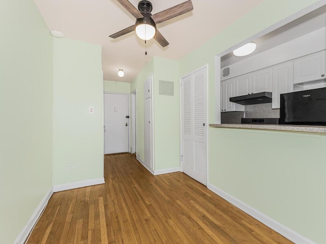 kitchen with black refrigerator, light hardwood / wood-style floors, white cabinetry, and ceiling fan