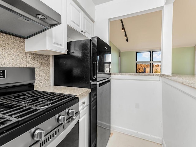 kitchen with light tile patterned floors, stainless steel gas range, backsplash, white cabinets, and exhaust hood