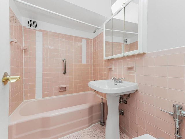 bathroom featuring sink, tile patterned flooring, tile walls, and tiled shower / bath