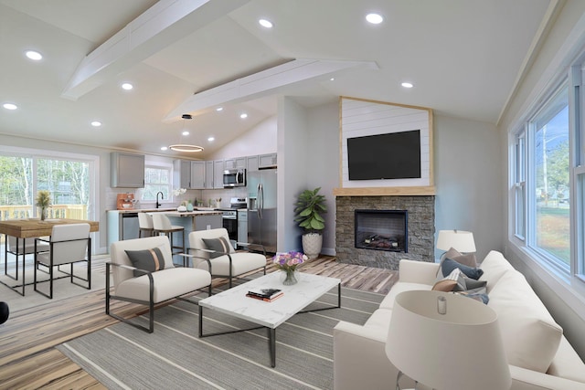 living room with sink, a fireplace, lofted ceiling, and light wood-type flooring