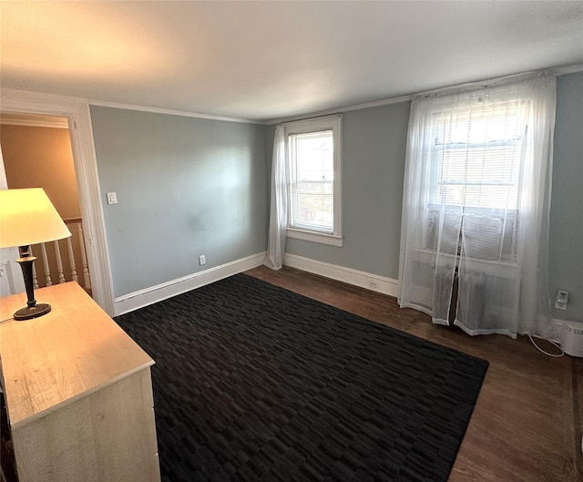 spare room featuring dark hardwood / wood-style flooring, crown molding, and plenty of natural light