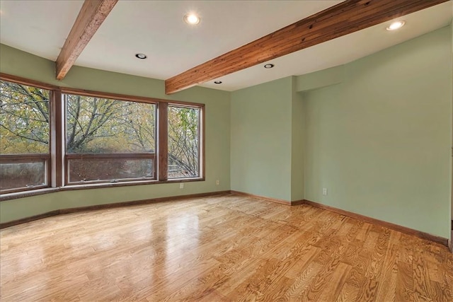 empty room with beamed ceiling and light wood-type flooring