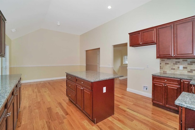 kitchen featuring light stone counters, a center island, lofted ceiling, and light wood-type flooring