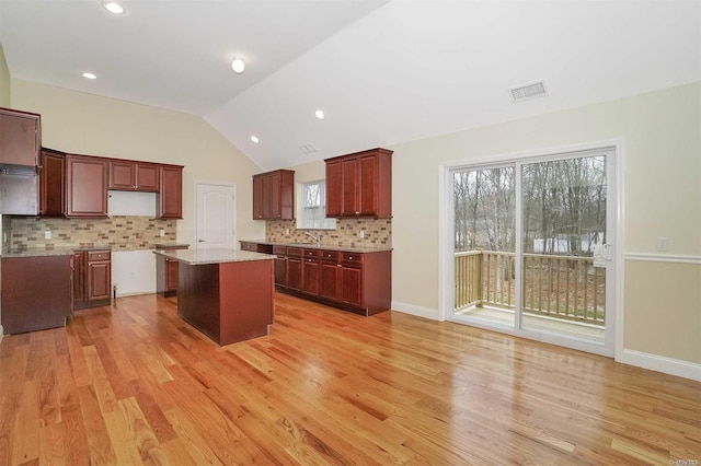 kitchen with a center island, tasteful backsplash, light hardwood / wood-style flooring, and lofted ceiling