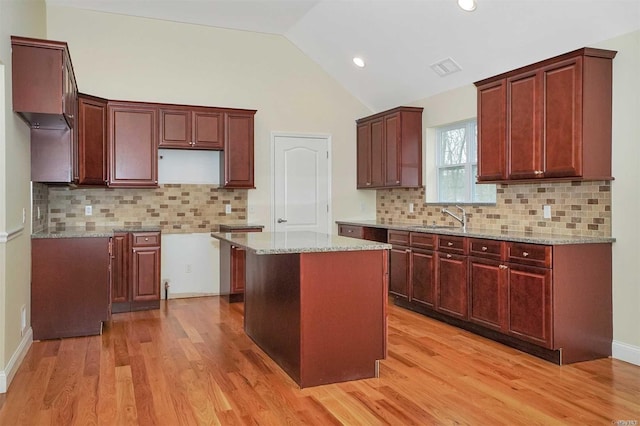 kitchen featuring a center island, tasteful backsplash, vaulted ceiling, and light hardwood / wood-style floors