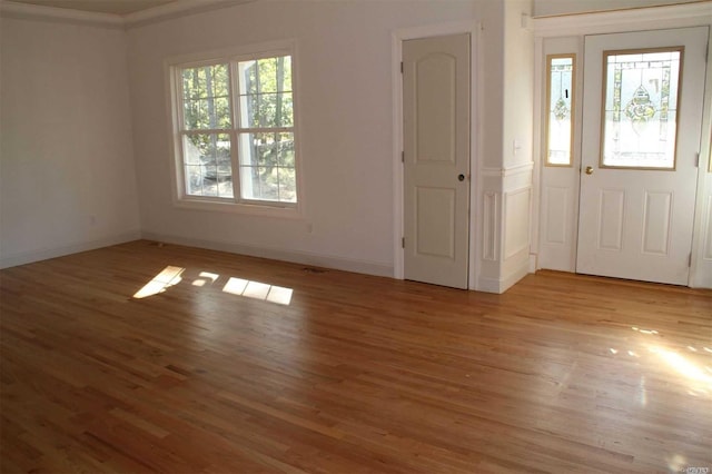 foyer entrance featuring crown molding, a healthy amount of sunlight, and light hardwood / wood-style floors