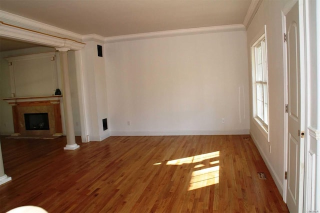 unfurnished living room featuring hardwood / wood-style flooring, ornamental molding, and ornate columns