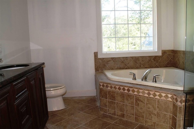 bathroom featuring tile patterned flooring, vanity, a relaxing tiled tub, and toilet