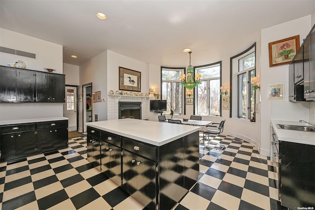 kitchen featuring sink, an inviting chandelier, a center island, hanging light fixtures, and a tiled fireplace