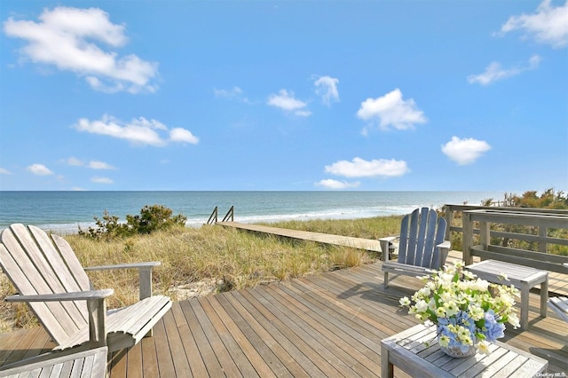 wooden terrace featuring a beach view and a water view