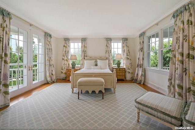 bedroom featuring french doors, crown molding, and light hardwood / wood-style flooring