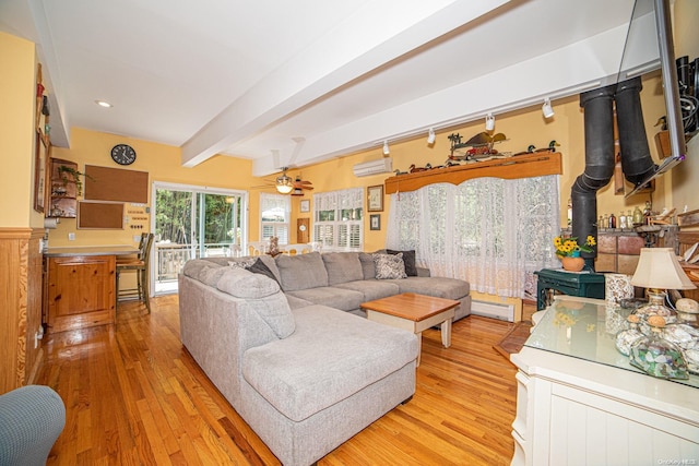 living room featuring ceiling fan, light hardwood / wood-style flooring, beamed ceiling, a baseboard heating unit, and an AC wall unit