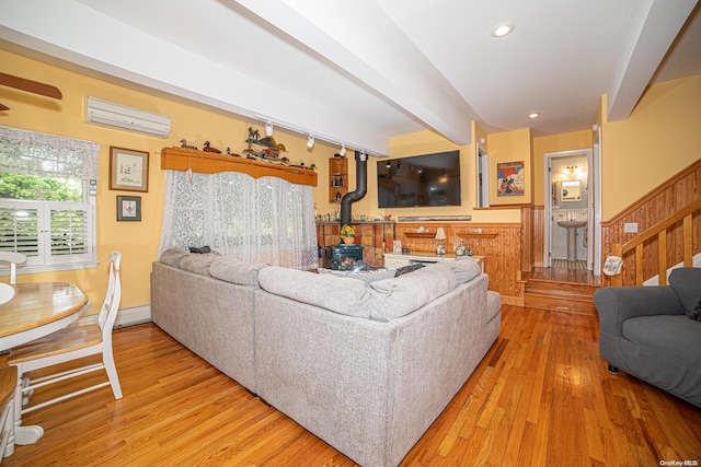 living room with beam ceiling, light hardwood / wood-style floors, and a wall mounted air conditioner