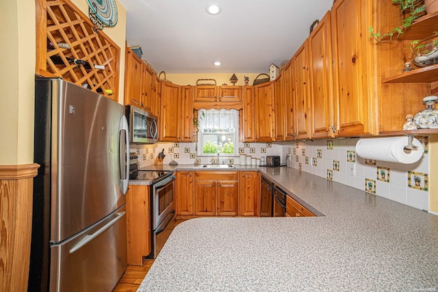 kitchen featuring kitchen peninsula, decorative backsplash, sink, and appliances with stainless steel finishes